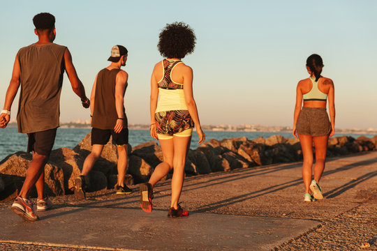 Back view of four sports people walking outdoors