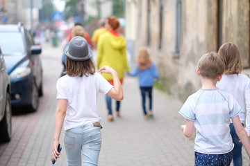 A small group of children is walking along the city street - 172053675