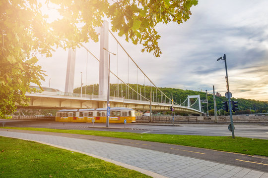 Budapest, Hungary - Traditional yellow tram passing by under the Elisabeth Bridge at the Danube with Gellert Hill at background