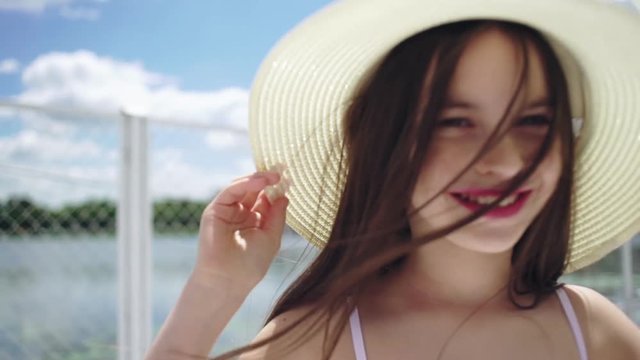 Pretty little girl in a striped dress and hat relaxing on the beach near sea, summer, vacation, travel concept. smiling cute little girl on beach vacation.
