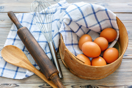 Kitchen utensils and brown eggs in an old sieve.