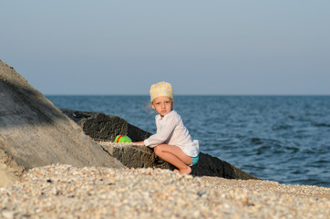 Little girl is played in the sand by the sea.