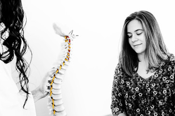 Doctor showing a hernia in a skeleton to female patient in the skeleton in silhouette isolated on white background. Color and black and white. Back pain