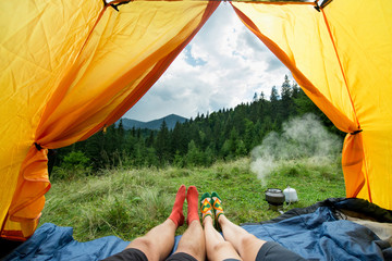 legs of a couples of man and woman in a tent outdoors