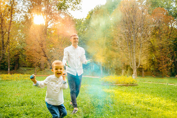 Fototapeta na wymiar Fathers and children in the park palys with holi paints