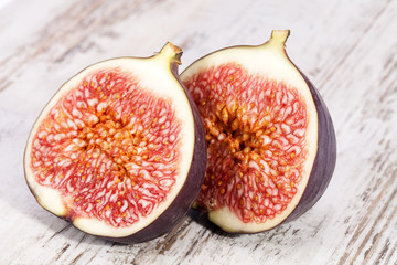 Fruits of half fresh figs on wooden plank, close up.