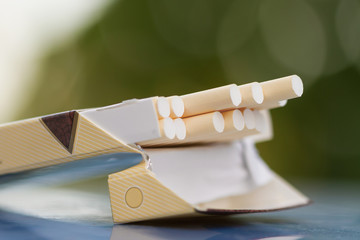 Open pack of cigarettes. Green blur background, closeup, selective focus