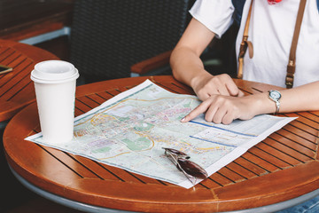 Fototapeta na wymiar Woman tourist travel holding map with cup of coffee in coffee shop