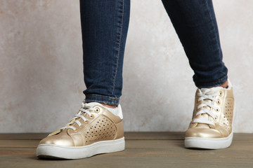 Female legs in gold sneakers