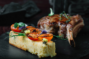 Grilled ribeye steak with polenta on dark background