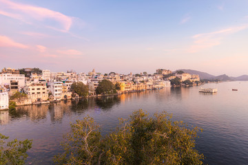 Fototapeta na wymiar Udaipur cityscape with colorful sky at sunset. The majestic city palace on Lake Pichola, travel destination in Rajasthan, India