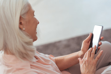 Cheerful senior woman using her smart phone at home
