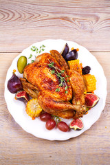 Whole chicken with fruits, vegetables and berries: figs, corn on cob, grape, plums and blackberry. View from above, top, vertical