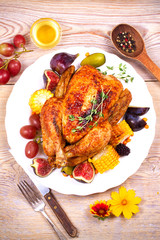 Whole chicken with honey, fruits, vegetables and berries: figs, corn on cob, grape, plums and blackberry