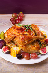 Whole chicken with fruits, vegetables and berries: figs, corn on cob, grape, plums and blackberry, vertical