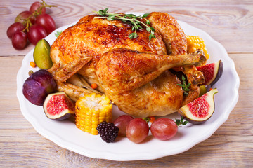 Whole chicken with fruits, vegetables and berries: figs, corn on cob, grape, plums and blackberry, horizontal