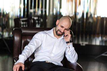 A brutal bald man talking on the phone.