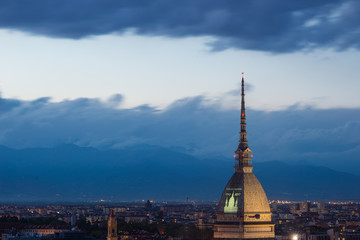 Cityscape of Torino (Turin, Italy) at dusk with dramatic sky over the Alps. The Mole Antonelliana towers on the city.