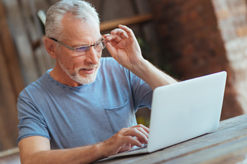 Concentrated aged man using laptop at home