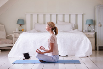 Woman With Digital Tablet Using Meditation App In Bedroom