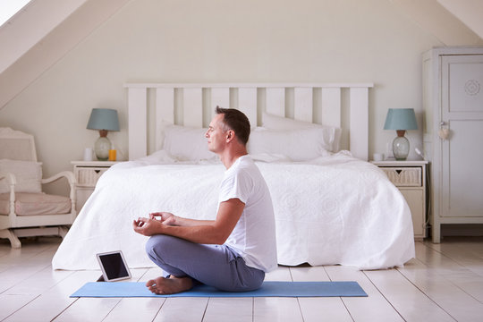Mature Man With Digital Tablet Using Meditation App In Bedroom