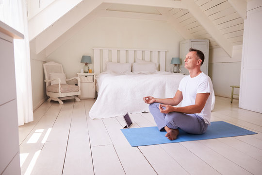 Mature Man With Digital Tablet Using Meditation App In Bedroom