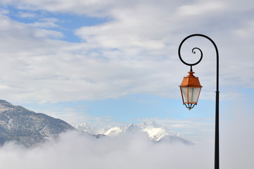 Fototapeta na wymiar lampadaire sur fond ciel et montagne enneigées