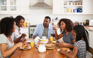 Family With Teenage Children Eating Breakfast In Kitchen - Powered by Adobe