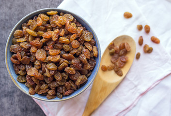 A raisin in the blue bowl . Wooden spoon.