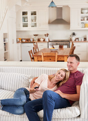 Couple Sitting On Sofa Watching Television Together
