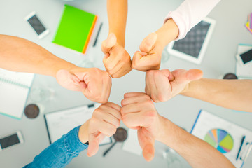 The six people thumb up at the table. view from above