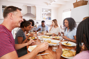 Two Families Enjoying Eating Meal At Home Together