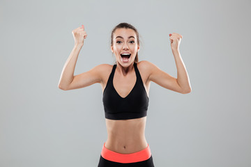 Fototapeta na wymiar Happy cheerful sportswoman celebrating success with arms raised