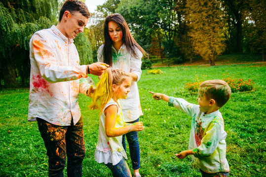 cute european family plaing with holi paints in the park