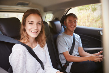 Fototapeta na wymiar Portrait Of Teenage Children In Back Seat Of Car On Road Trip