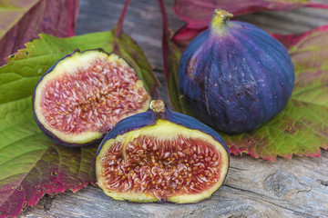 juicy violet fig fruit on rustic background and autumn leaves
