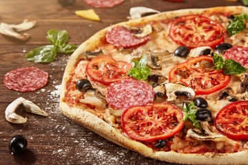 Fresh pizza with tomatoes, cheese and mushrooms on wooden table