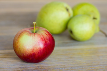 Closeup apple and pears on background / Red apple and green pears on wooden table
