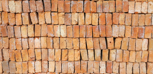 New red brick pavers stacked in rows like wall. Store of bricks ready for building or sale. Construction materials and outdoor storage. Abstract background.