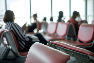 Blur background of people waiting at airport. blinding backlight from window, with empty chair seat in airport hall / lounge. Concept of lifestyle, tourism, holiday, travel.