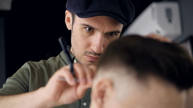 A focused barber uses a straight razor.   