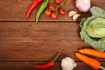Fresh vegetables on a wooden background. Garlic, cabbage, chili and cherry tomato. Harvest. Thanksgiving Day. Space for text. Background