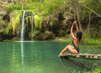 Beautiful woman relaxing near tropical waterfall