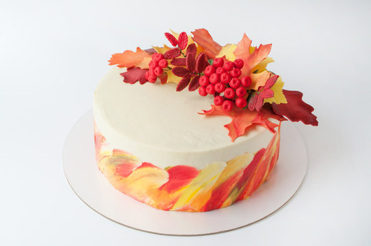 Art cake with whipped yellow, orange and green cream, decorated with autumn leaves from mastic. Picture for a menu or a confectionery catalog.