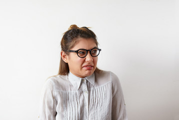 Negative human expressions, emotions, feelings, reaction and attitude. Studio shot of young Caucasian female employee wearing glasses and formal shirt, grimacing, having displeased disgusted look