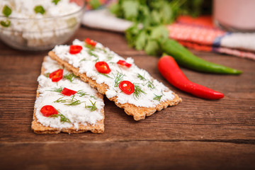 Bread with cottage cheese and chili pepper, with a bowl of cottage cheese with greens on a wooden background. Proper nutrition. Breakfast.
