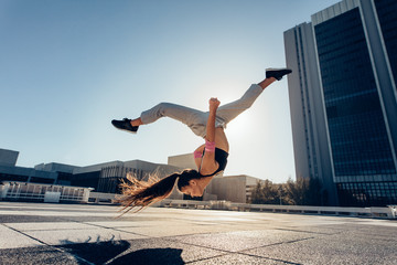 Urban woman performing a frontflip in city
