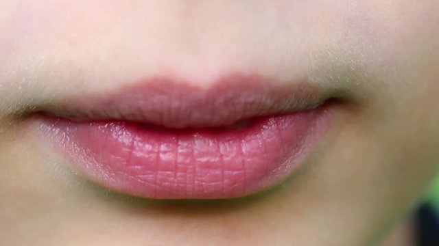 Closeup view of cute pink lips of young caucasian boy moving while he speaks. Child smiles after short talking. Real time full hd macro video footage.