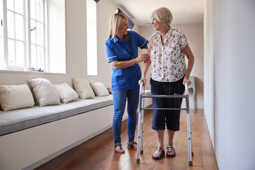 Nurse helping senior woman use a walking frame