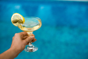 Bright martini cocktail on the pool background in hand © Iulia